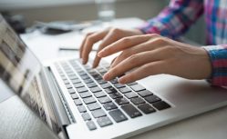 Cropped View of Hands Typing on Laptop